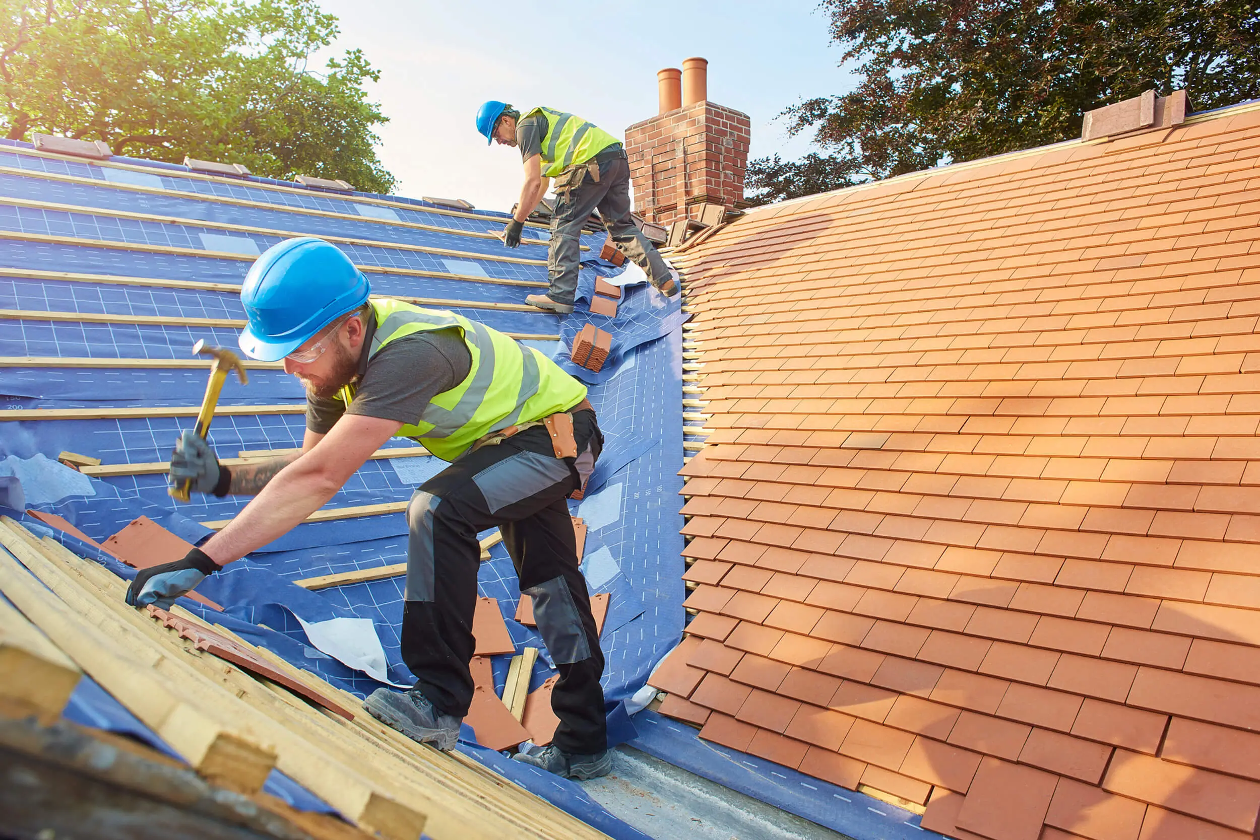 Workers installing roof tiles on a sunny day.